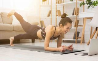Mulher treinando em casa assistindo vídeos no laptop