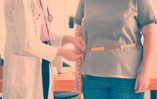 Médica com fita métrica medindo a circunferência abdomnial de uma paciente, mulher, para controle de peso, inlustrando o conceito de accountability na medicina e, principalemnte, na endocrinologia.